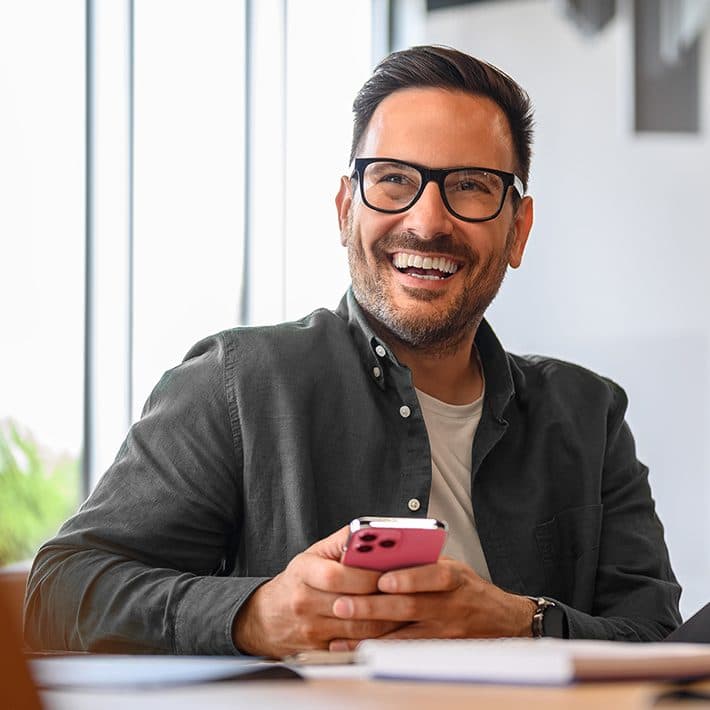 Homem feliz segurando um celular na cor rosa em suas mãos