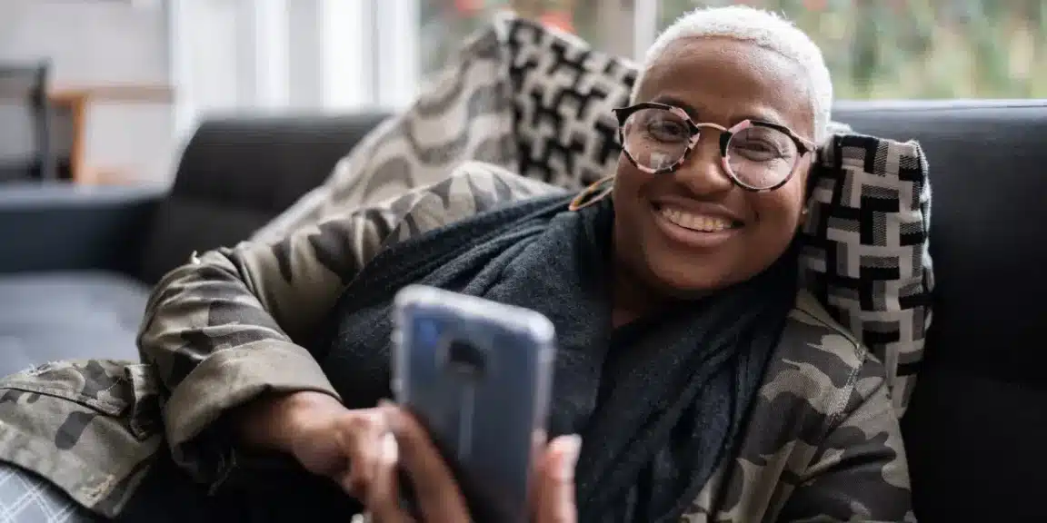 mulher sorrindo ao olhar pro celular