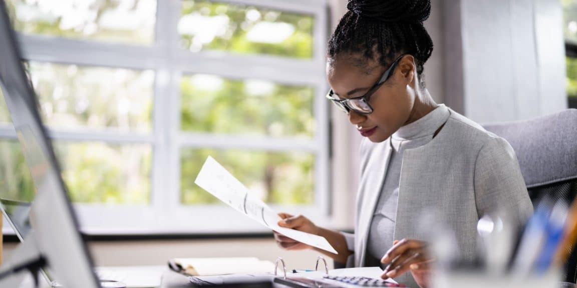 Empreendedora na mesa do seu escritório preparando cobranças para clientes após aprender como emitir boletos de graça.