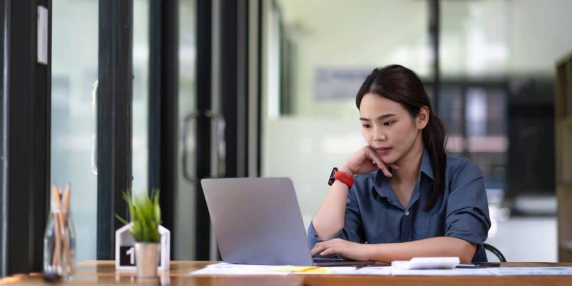 mulher sentada olhando para o computador e consultando o seu score